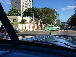 An old car in Havana Cuba with a wall reading Viva la Cuba!